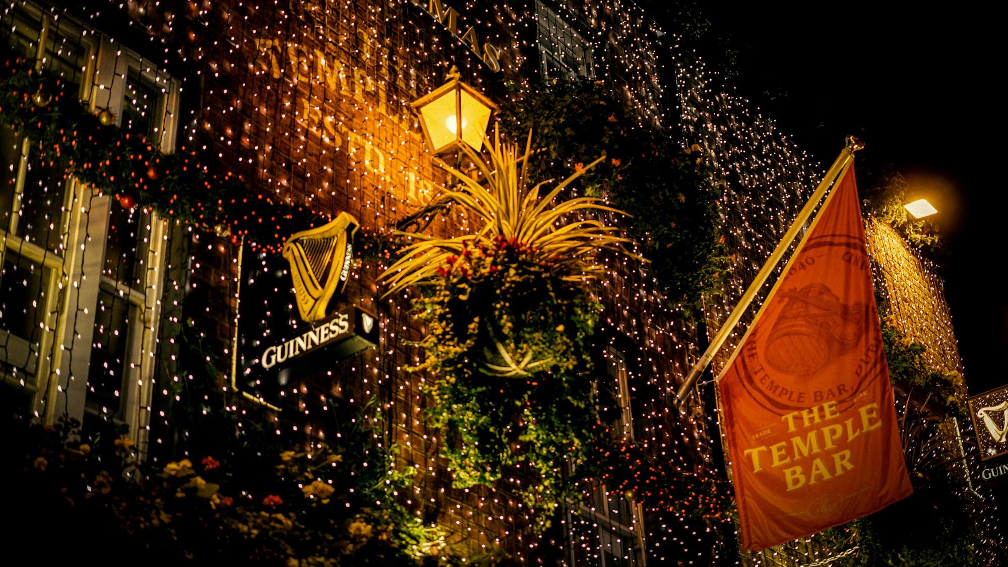 The Temple Bar pub in Dublin, Ireland decorated with Christmas lights and a tree at night