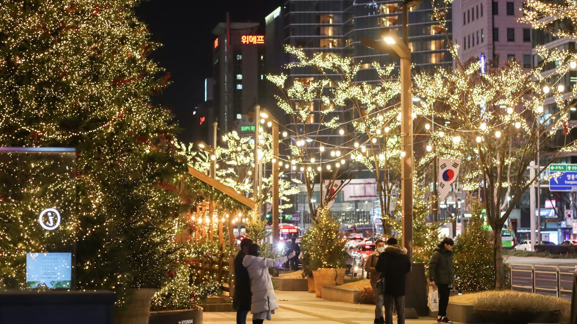 People walking down a Seoul street covered in Christmas lights at night, South Korea